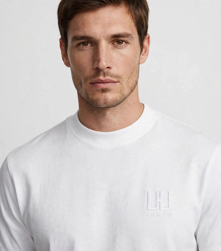 A man wearing the white t-shirt, shown close, with the embroidered mark on the chest.